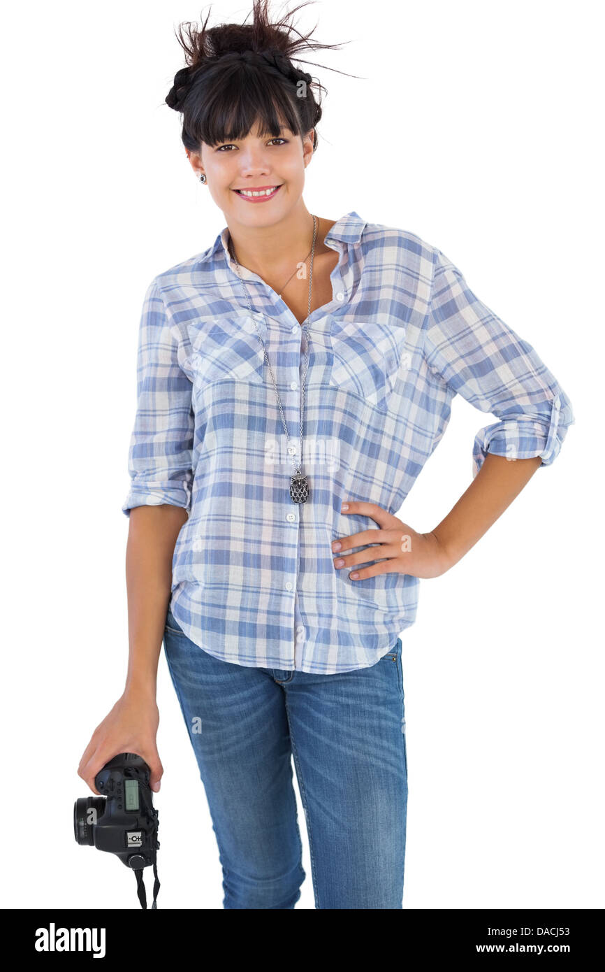 Smiling brunette holding camera avec sa main sur la hanche Banque D'Images