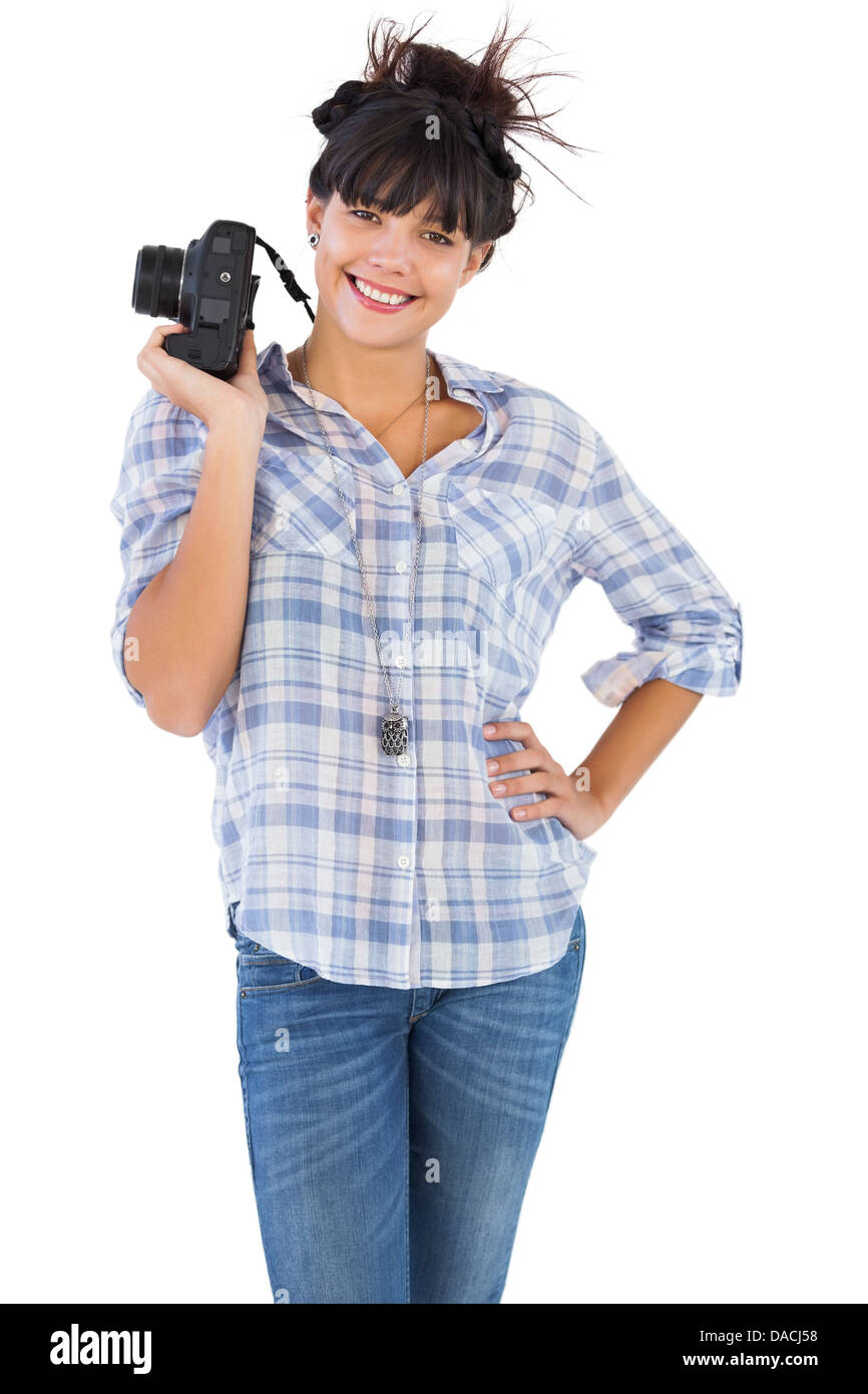 Belle femme souriante avec sa main sur la hanche et tenir l'appareil photo Banque D'Images