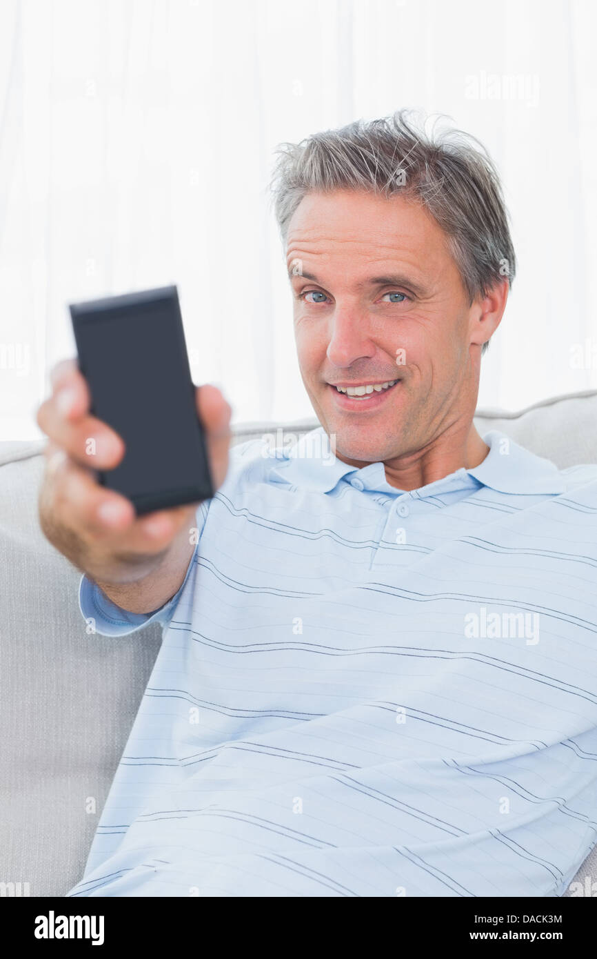 Montrant l'homme à l'appareil photo du smartphone and smiling Banque D'Images