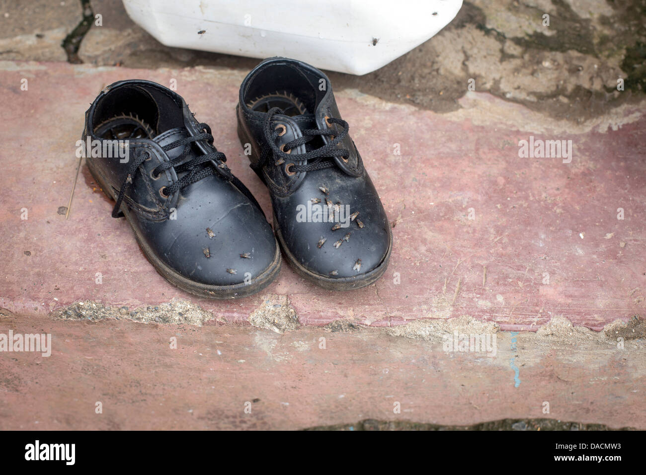 L'Inde les bidonvilles petit enfant chaussures femme avec vole sur sur un mur Banque D'Images