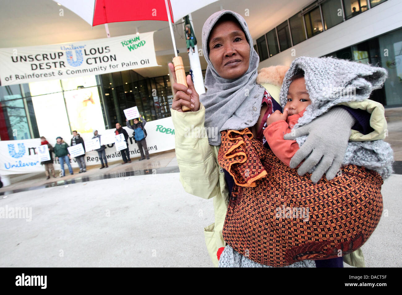 Militant de l'Indonésie et de l'Ida son fils âgé d'un an Agung protester ensemble avec des militants de l'organisation de protection de l'environnement Robin des bois en face de l'Unilever construire à Hafencity à Hambourg, Allemagne, le 14 décembre 2011. Des militants de la protection de l'environnement à appeler l'attention sur la destruction des forêts tropicales indonésiennes pour la production d'huile de palme avec la c Banque D'Images