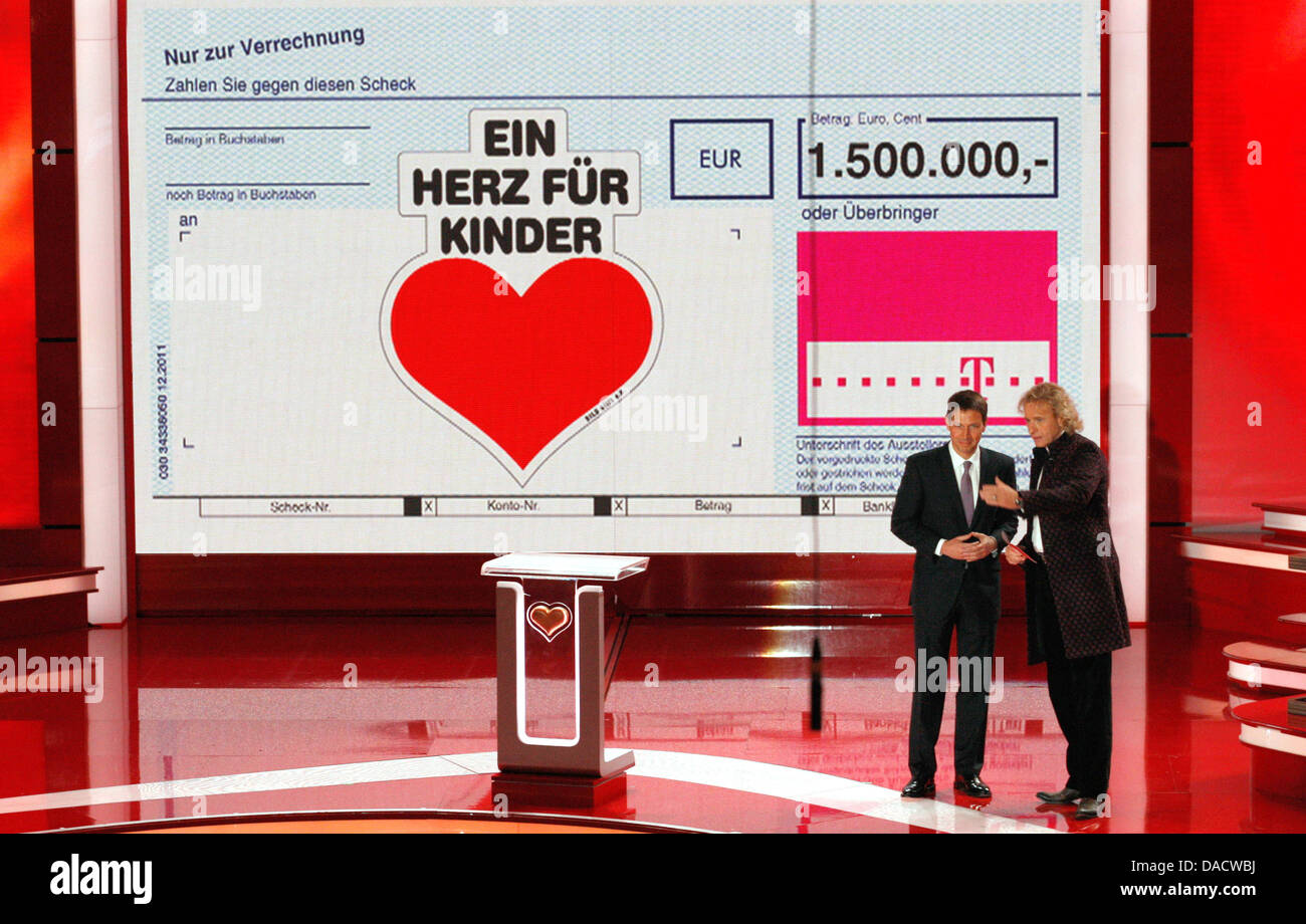 Thomas Gottschalk hôte (R) se tient sur scène avec Deutsche Telekom CHEF Rene Obermann devant un géant vérifier au cours de la 'Ein Herz für Kinder" (Un coeur pour les enfants) TV téléthon Charité à Berlin, le 17 décembre 2011. Photo : Tobias Schwarz dpa  + + +(c) afp - Bildfunk + + + Banque D'Images
