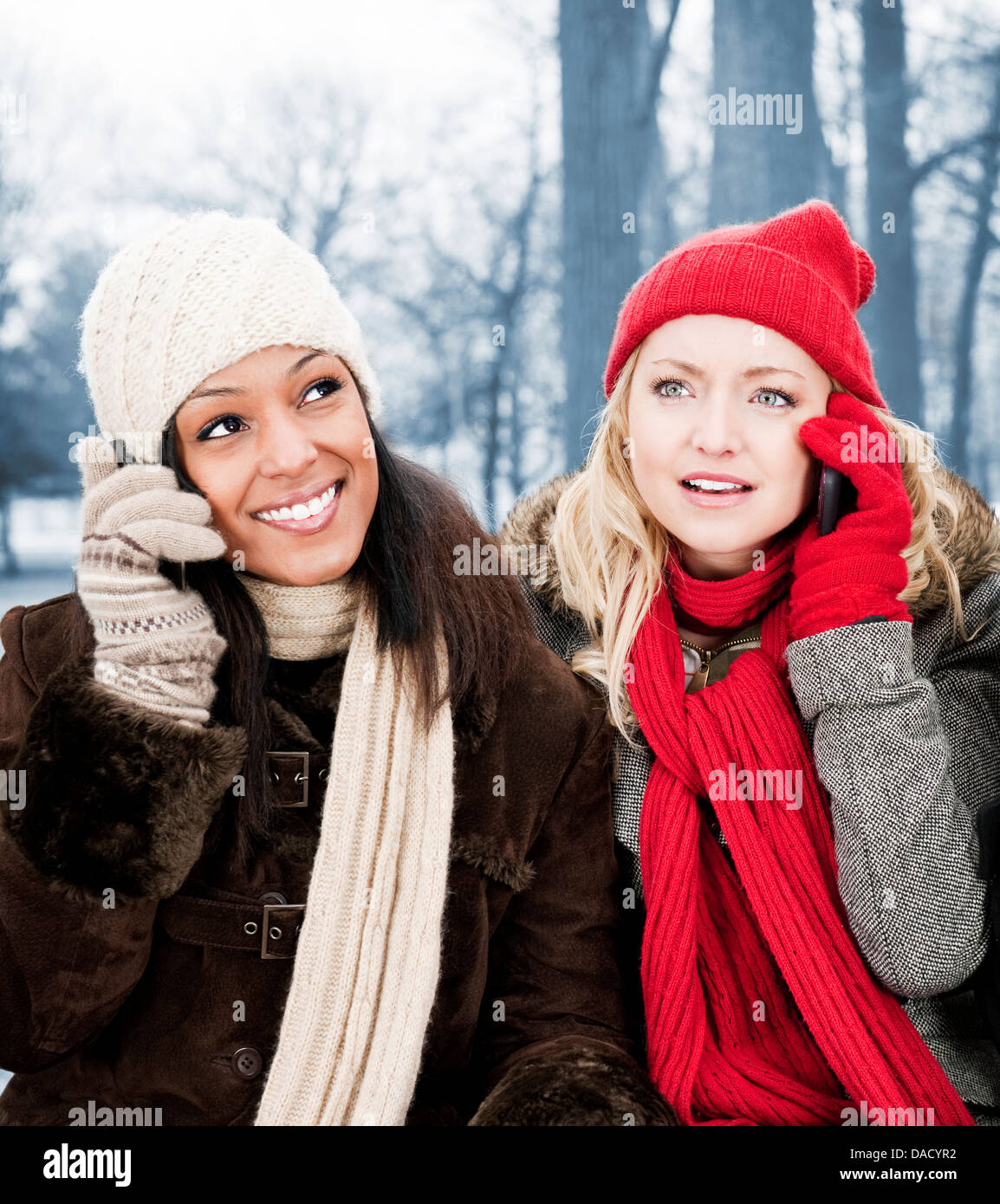 Portrait de deux jeunes amis féminins sur le téléphone à l'extérieur en hiver Banque D'Images
