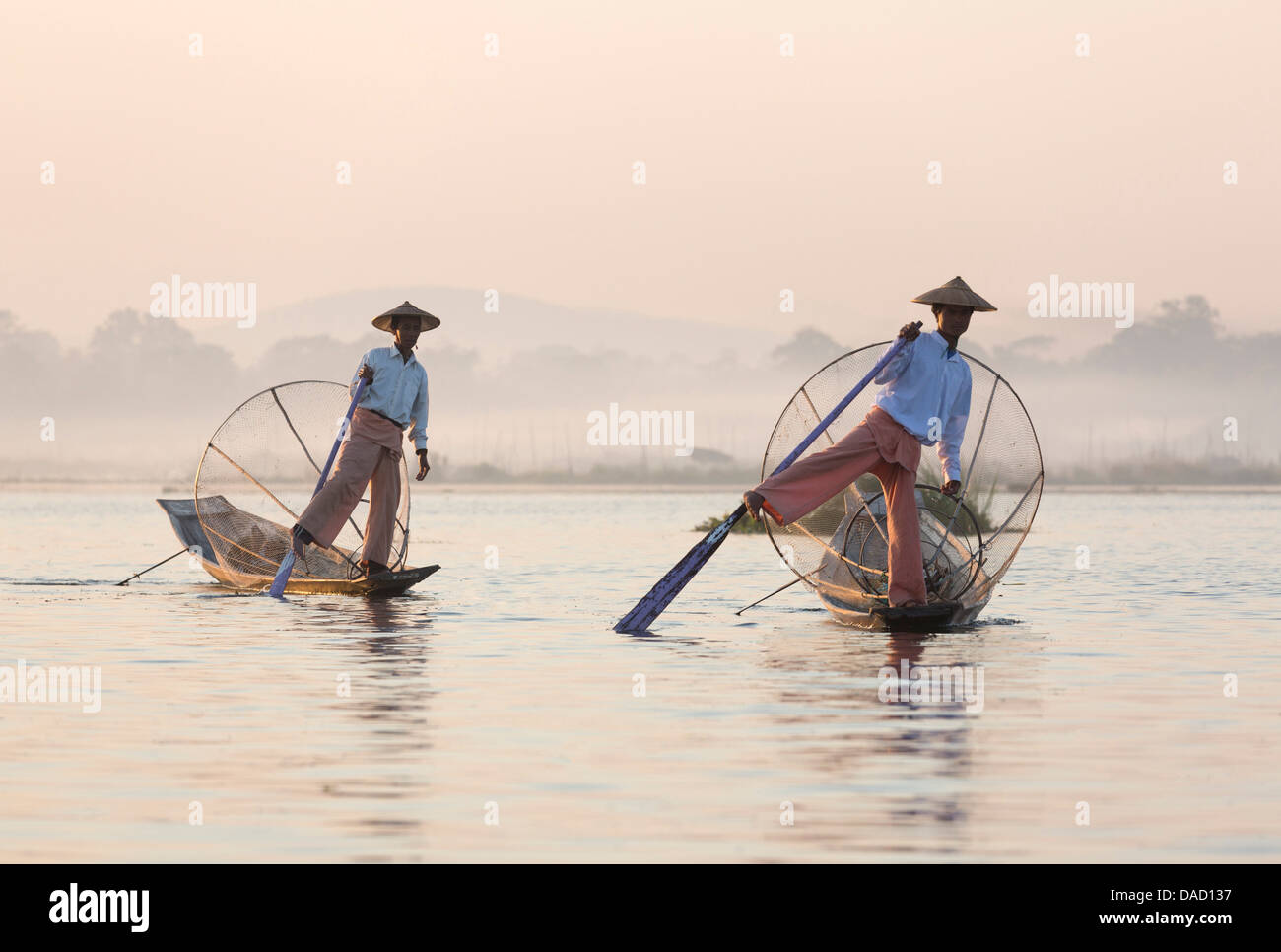 'Aviron' ethnie Intha jambe pêcheurs au coucher du soleil sur le lac Inle, lac Inle, Myanmar Banque D'Images