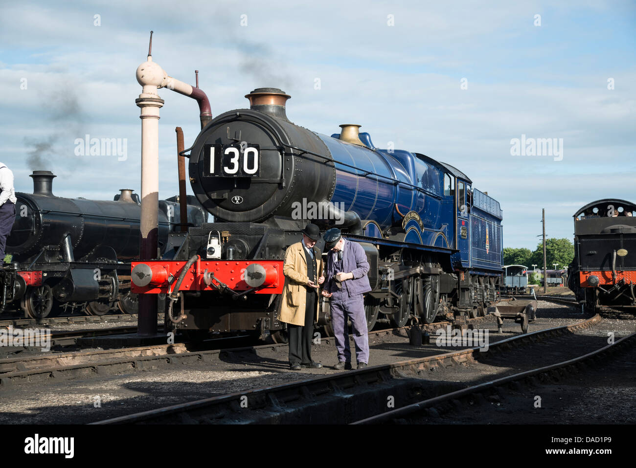 Contremaître conducteur et vérifier l'heure debout devant la locomotive à vapeur historique de 6023, le roi Édouard II à Didcot Railway Centre. Banque D'Images