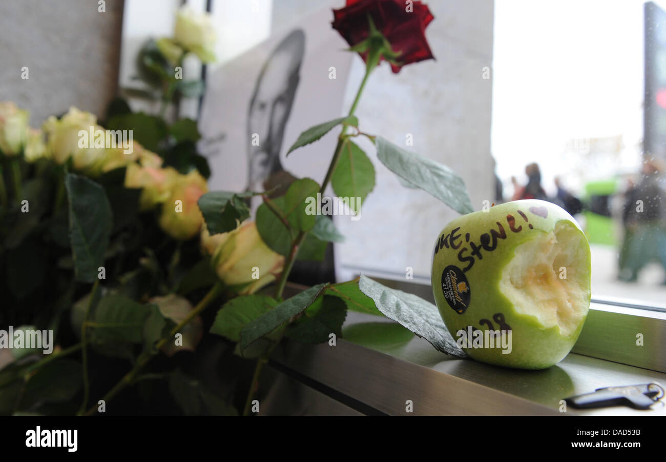 Fleur se trouvent en regard d'une photo du décès du fondateur d'Apple Steve Jobs à l'Apple Store de Hambourg, Allemagne, 06 octobre 2011. Steve Jobs, fondateur et PDG de longue date d'Apple, est mort mercredi en Californie. Emplois avaient été atteints de cancer pendant des années. Il a été vu comme le moteur de nombreux développements dans le domaine de l'informatique. Photo : MARCUS BRANDT Banque D'Images