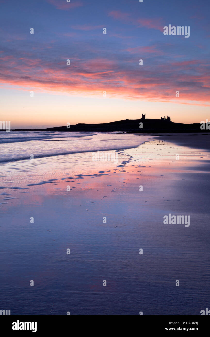 À travers la baie Embleton au lever du soleil vers les ruines du château de Dunstanburgh, Embleton, près de Alnwick, Northumberland, England, UK Banque D'Images