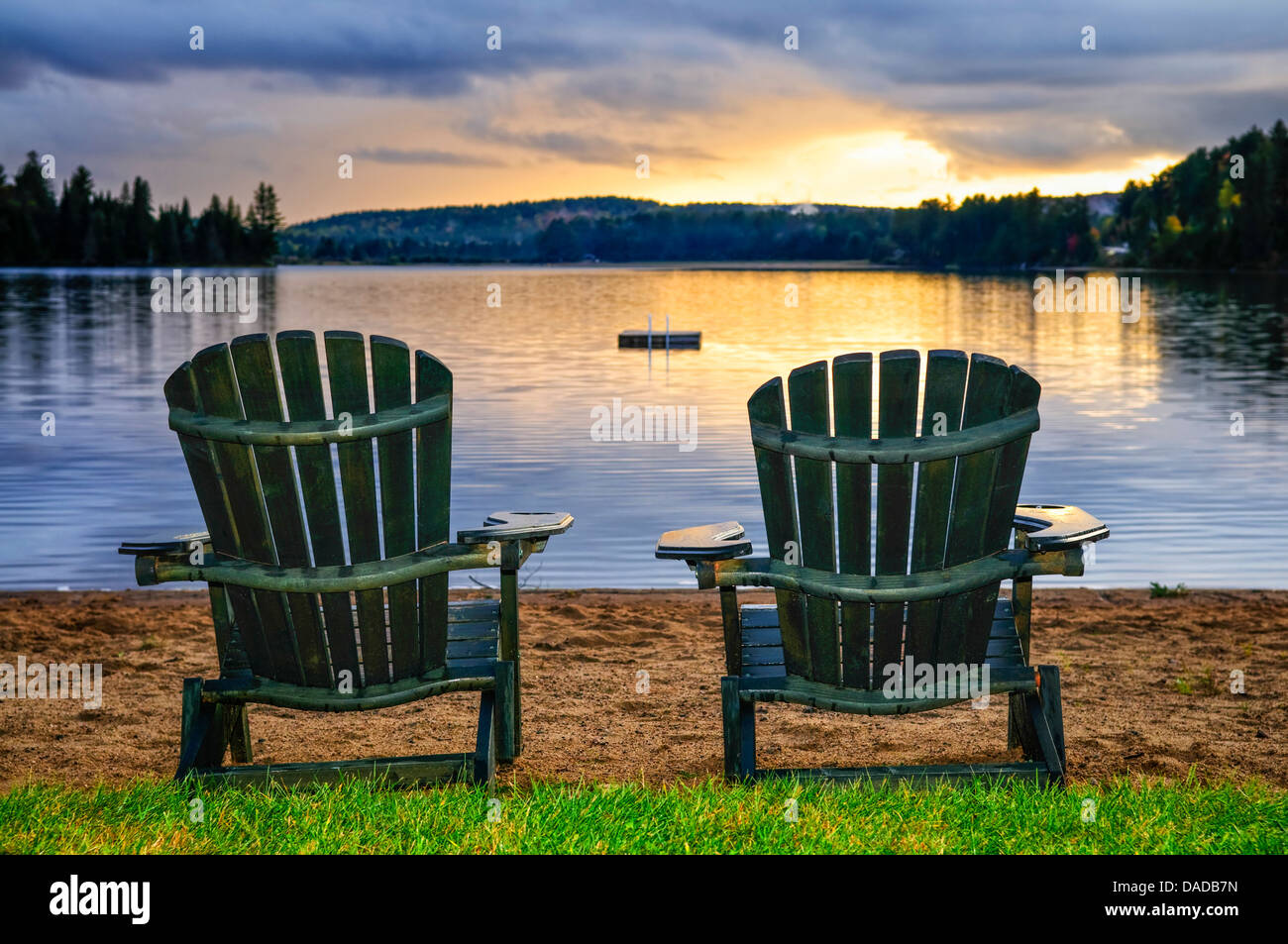 Deux chaises en bois sur la plage du lac de détente au coucher du soleil. Le parc provincial Algonquin, au Canada. Banque D'Images