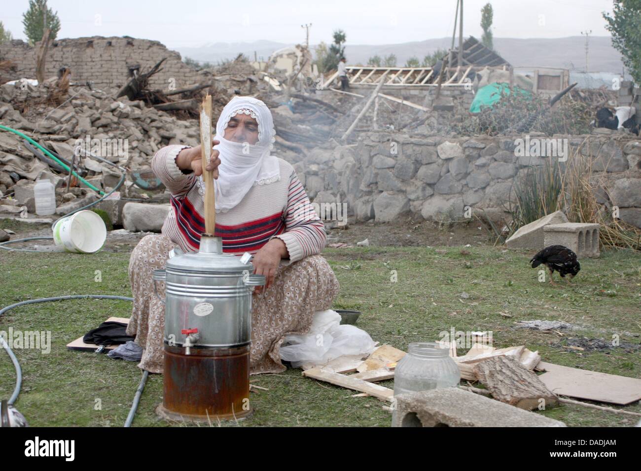 Grand-mère Talia recharges Ileri son thé de l'urne en face de vestiges de sa maison et ses voisins en Gedikbulak maisons, la Turquie, le 26 octobre 2011. Tous les bâtiments de son village a été rasé ou rendue dangereuse par le tremblement de terre de magnitude 7,2 qui a frappé l'est de la Turquie le dimanche 23 octobre 2011. Photo : JASPER MORTIMER Banque D'Images