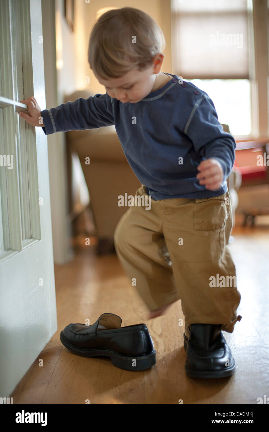 Garçon essayant sur chaussure d'adultes Banque D'Images
