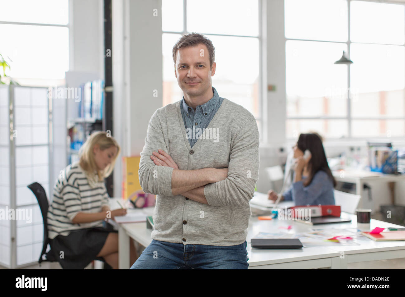 Man sitting on desk and smiling in creative office, portrait Banque D'Images