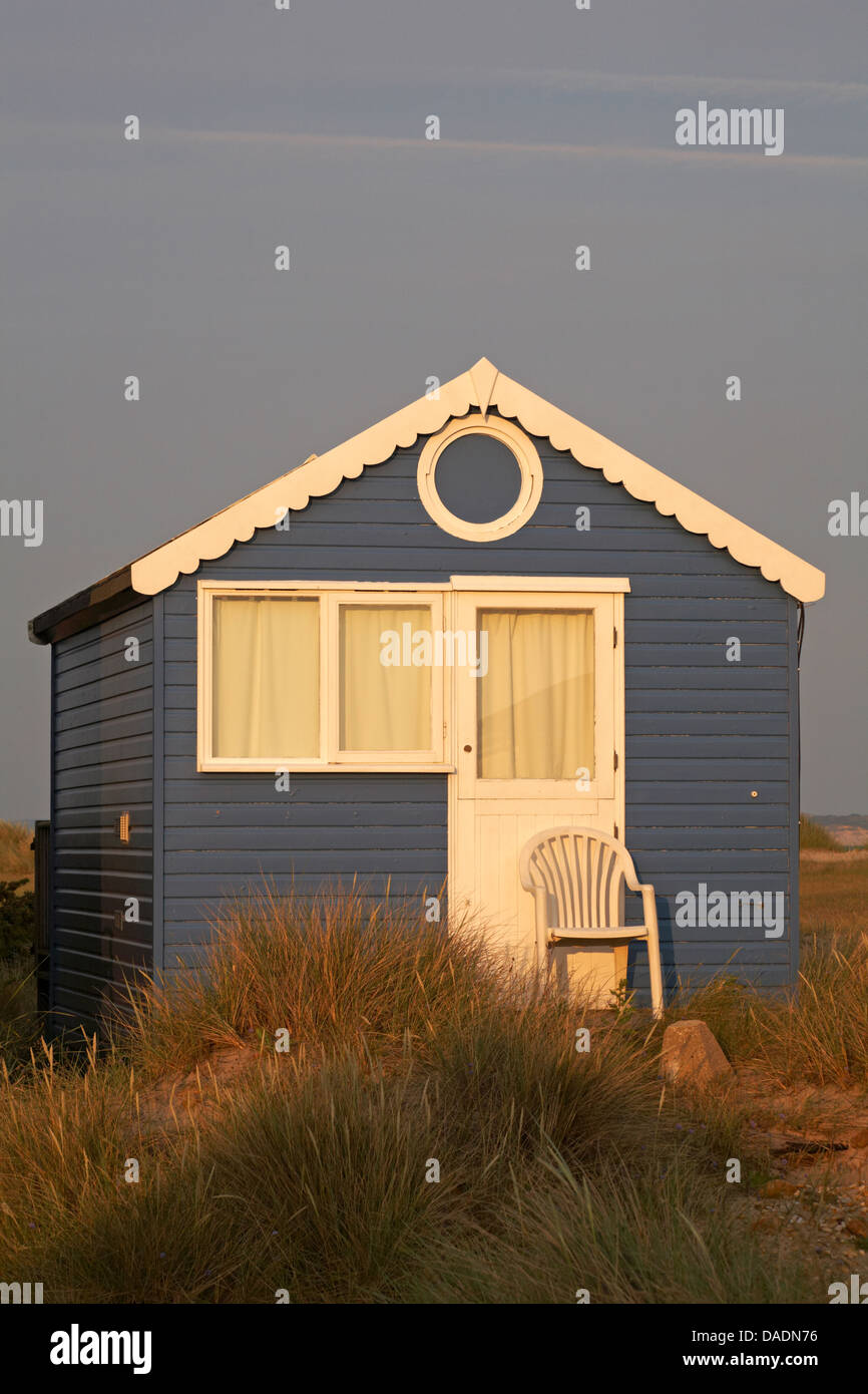 chaise placée à l'extérieur de la hutte de plage bleue en se prélassant dans la lumière du soir à Hengistbury Head, Mudeford Spit, Christchurch, Dorset UK en juin Banque D'Images