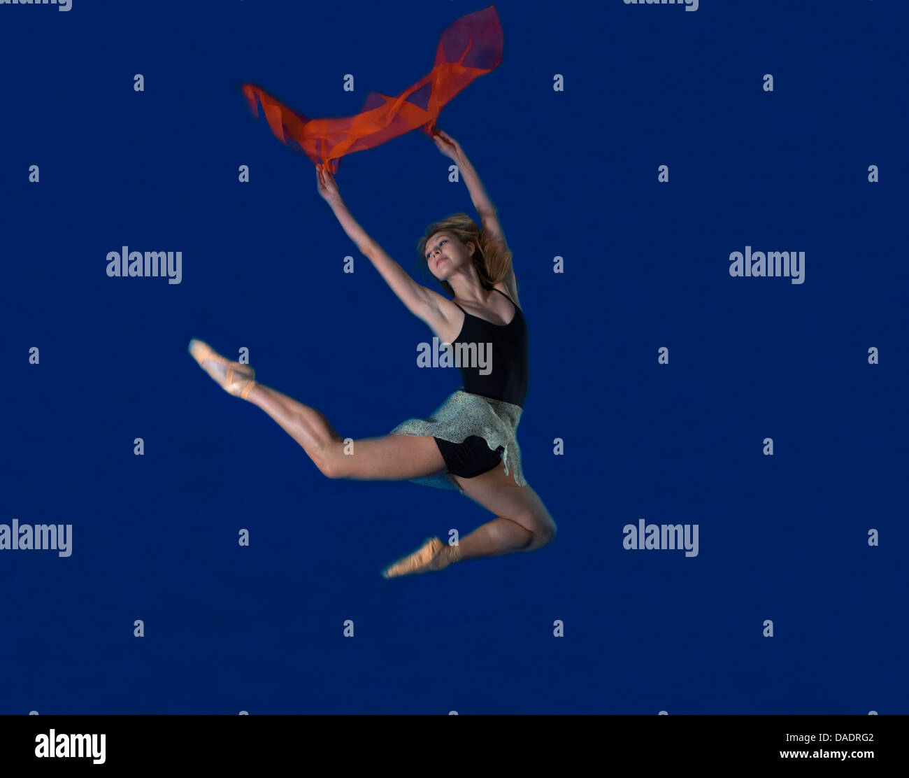 Jeune danseuse jumping mid air avec l'écharpe rouge Banque D'Images