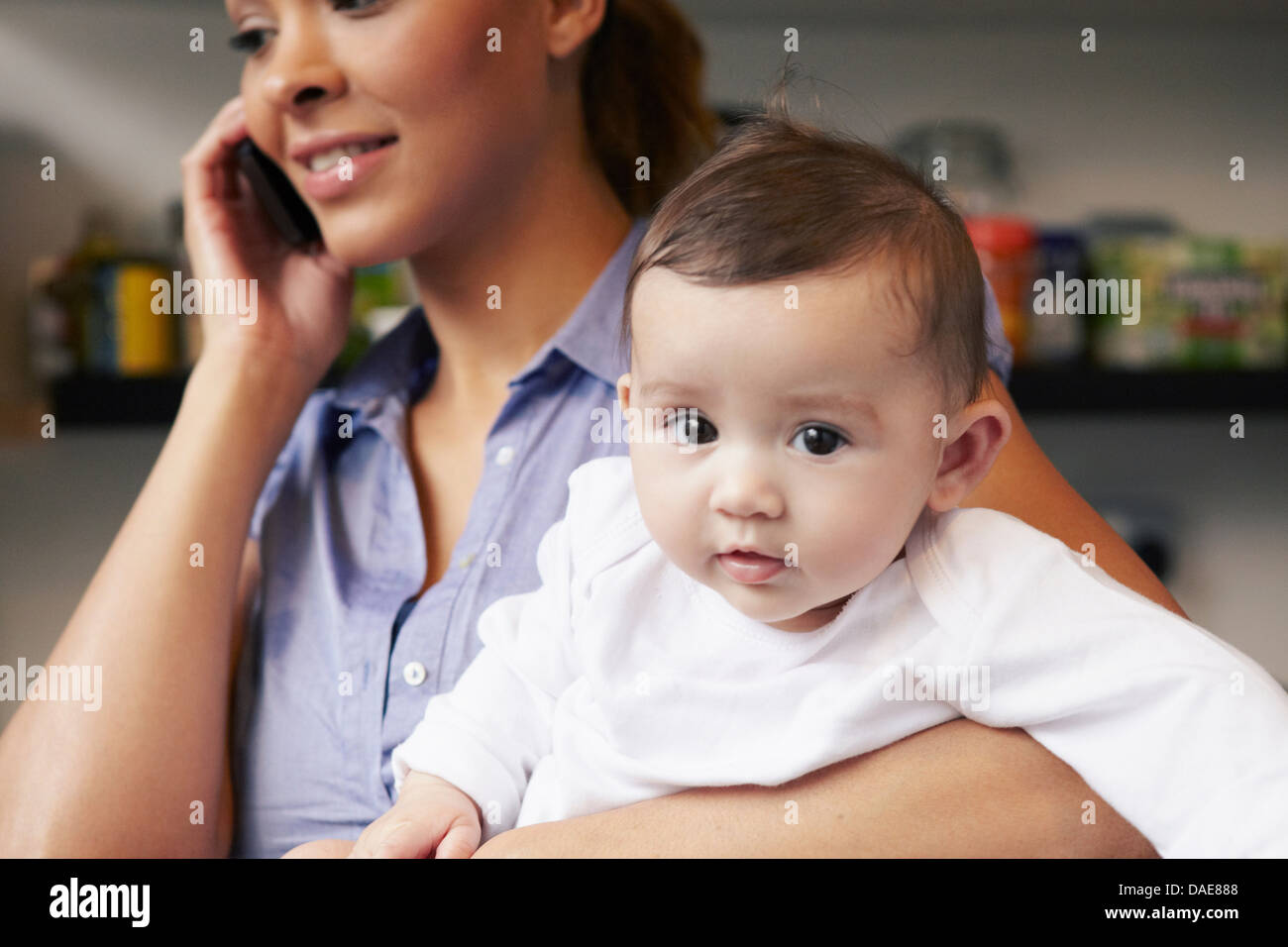 Mother holding baby girl alors que sur le téléphone Banque D'Images