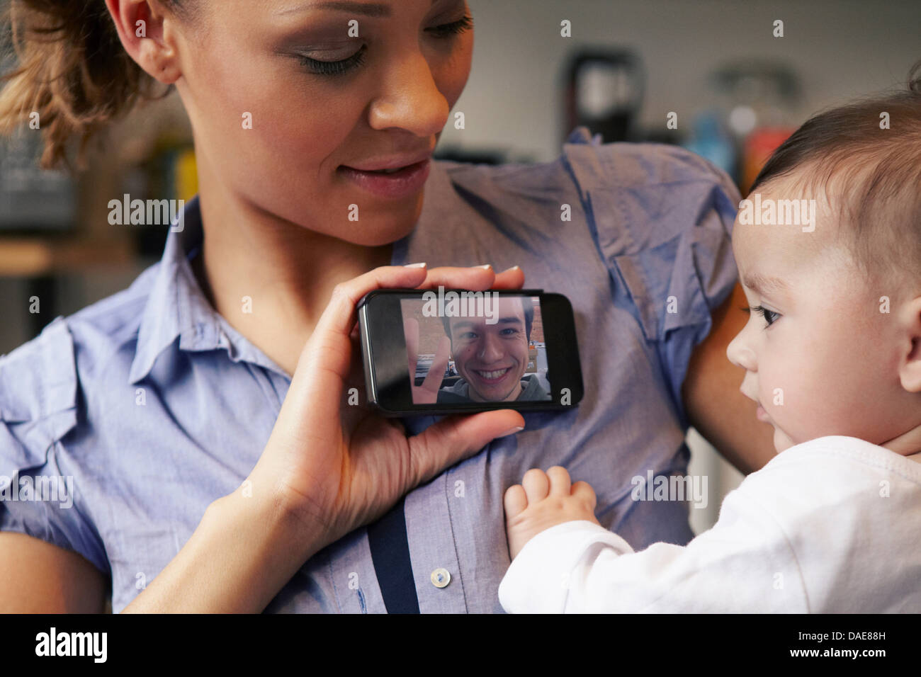 Baby Girl watching father sur appel vidéo, mère holding smartphone Banque D'Images