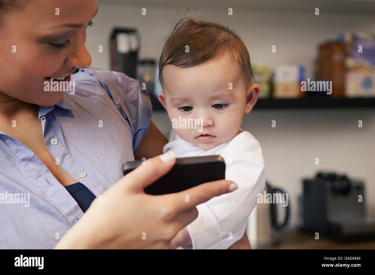 Mère montrant baby girl téléphone intelligent Banque D'Images