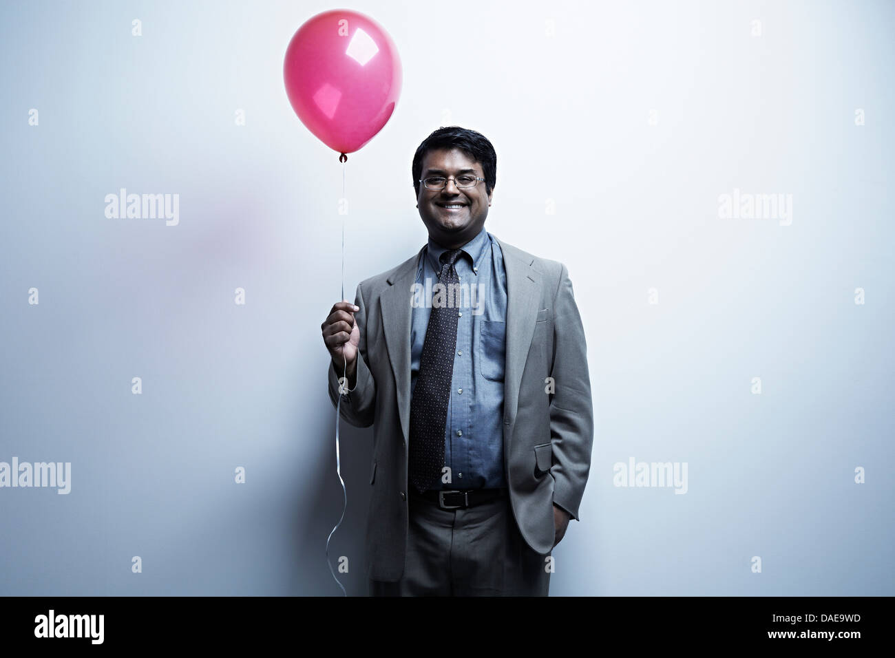 Studio portrait of businessman holding ballon rouge Banque D'Images