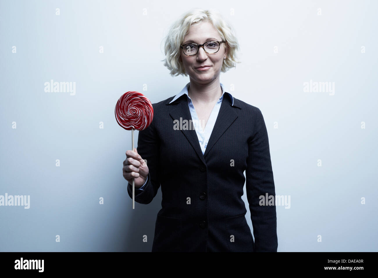 Studio portrait of blond businesswoman with red lollipop Banque D'Images