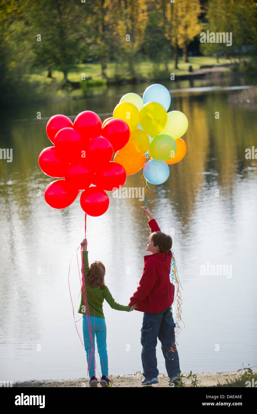 Frère et soeur avec bouquets de ballons dans l'park Banque D'Images