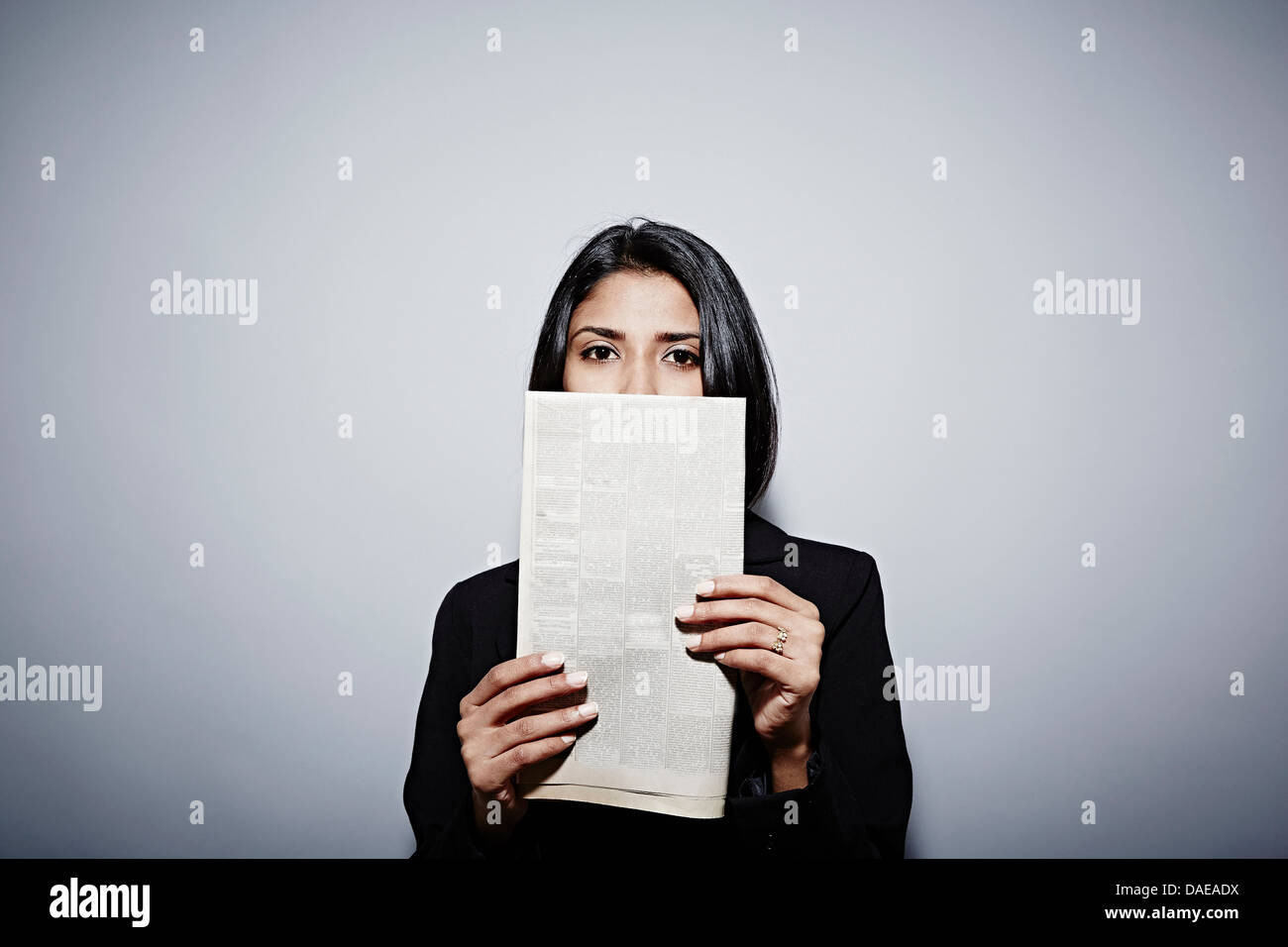 Studio portrait of businesswoman holding up newspaper Banque D'Images