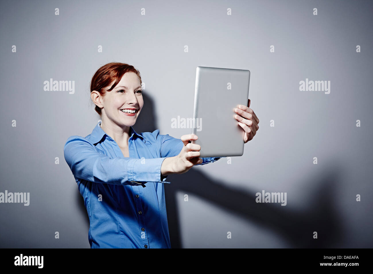 Studio portrait of young woman holding up digital tablet Banque D'Images