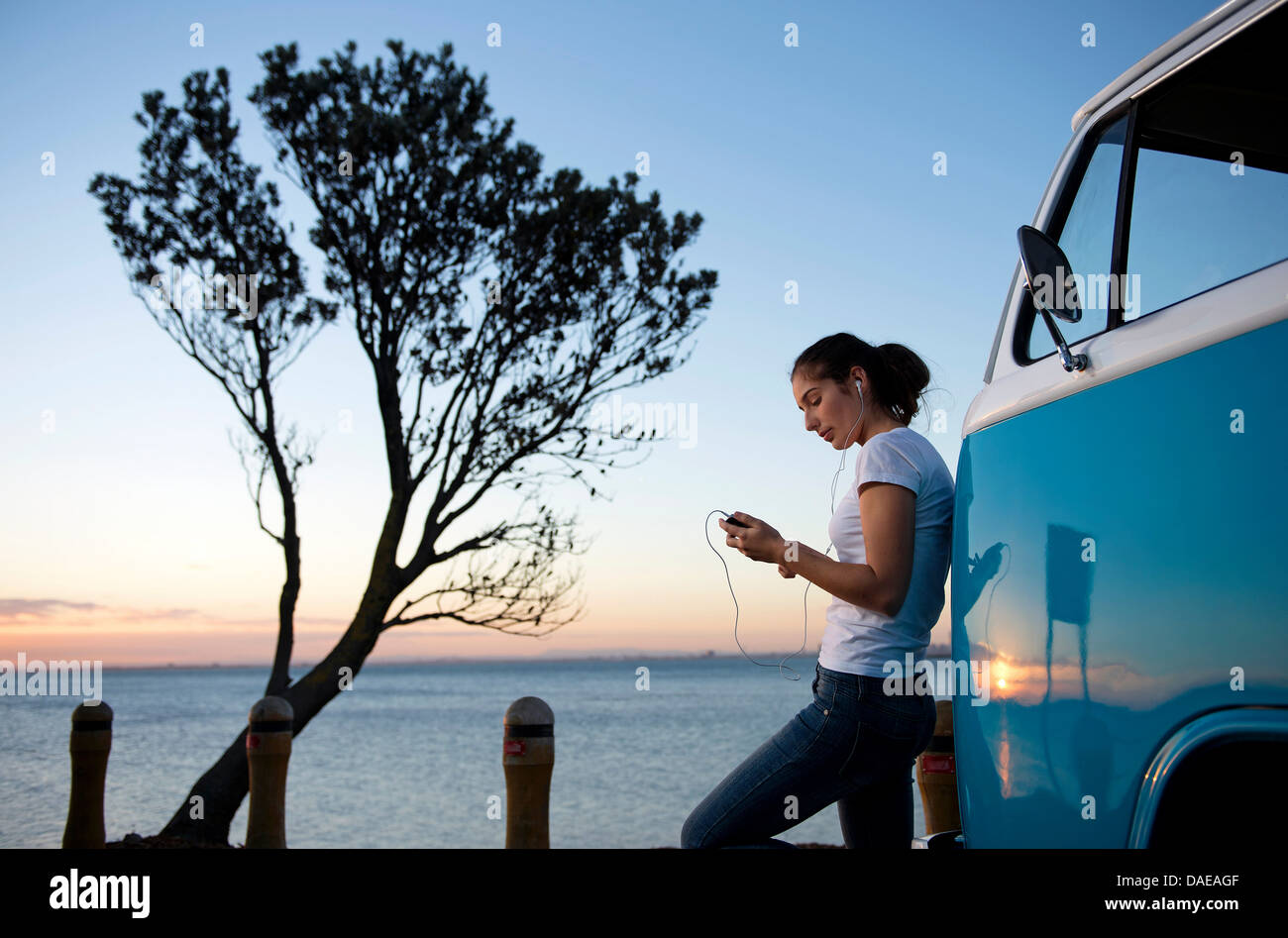 Young woman leaning on camper van au crépuscule Banque D'Images