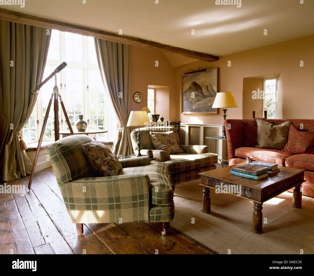 Fauteuils à carreaux roses et Knole canapé avec table basse en bois indonésien en pays salon avec tapis sur un plancher en bois Banque D'Images