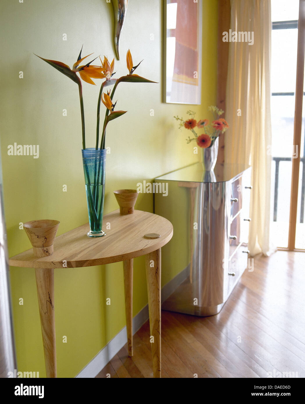 Les oiseaux de paradis des fleurs dans vase sur console en bois clair table in modern lime green hall avec metal poitrine-de-tiroirs Banque D'Images