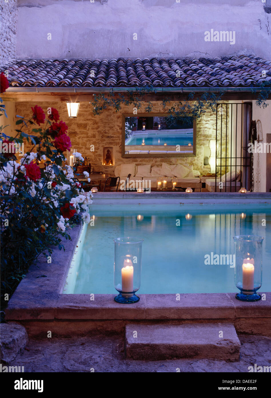 Des bougies dans des lanternes en verre sur le bord de piscine en face de  la bougie avec loggia couverte miroir sur le mur Photo Stock - Alamy