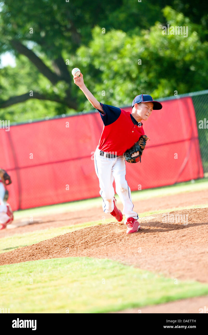 La petite ligue de baseball boy pitching lors d'une partie. Banque D'Images