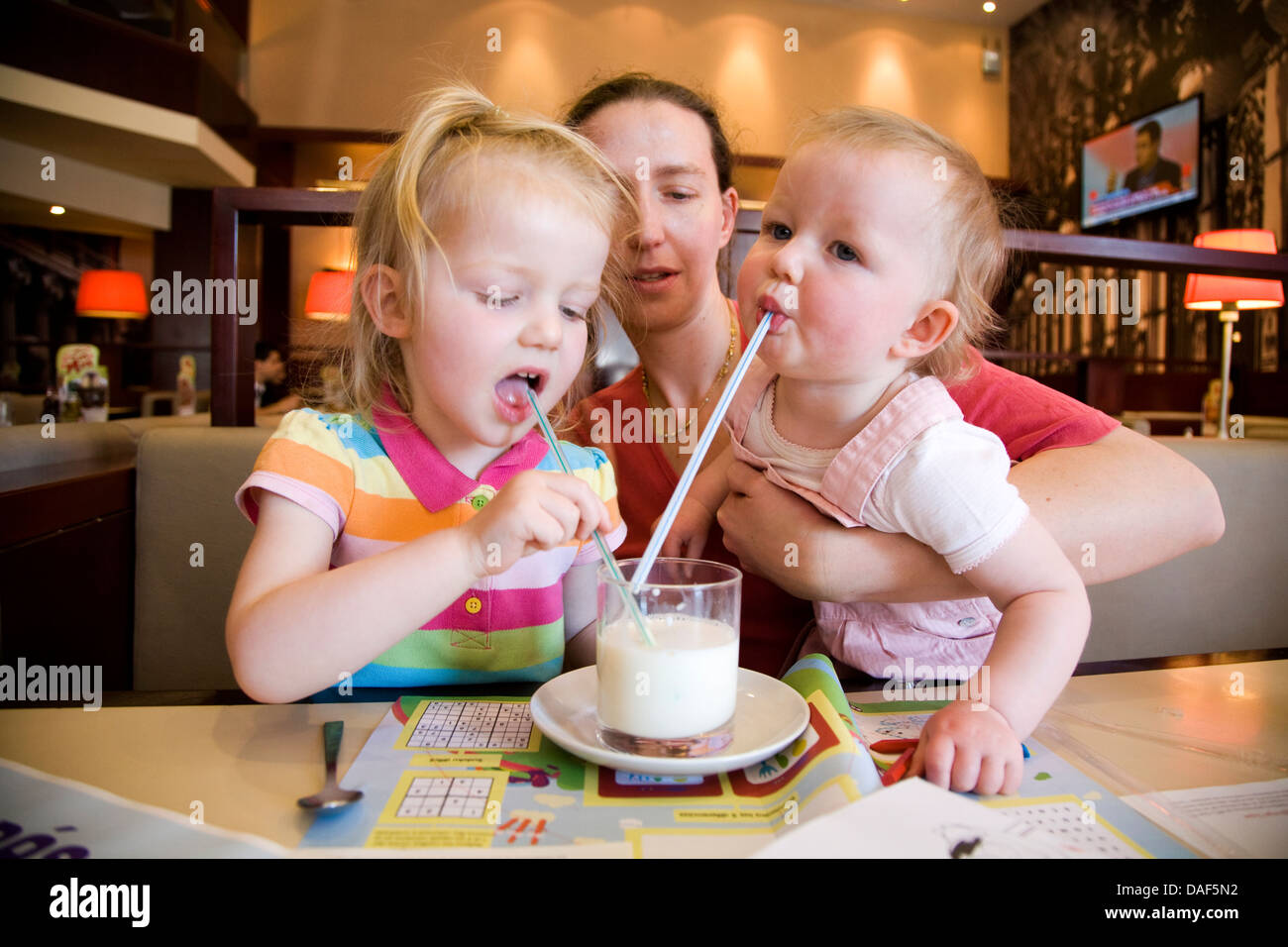 Deux 2 Enfants Enfant Et Bebe Verre De Lait De Vache Avec Paille Pailles Tenu Par La Mere Dans Un Cafe Restaurant Photo Stock Alamy