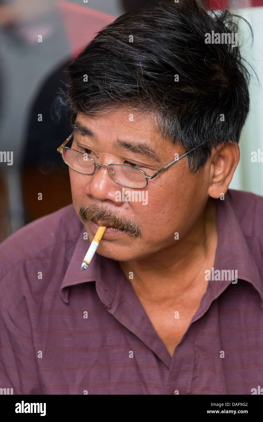 Fumeurs vietnamiens l'homme dans les rues du vieux quartier de Hanoi, Vietnam Banque D'Images