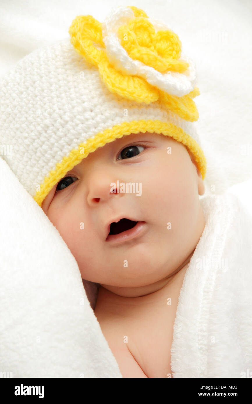 Bébé avec un chapeau blanc tricoté avec une fleur Banque D'Images