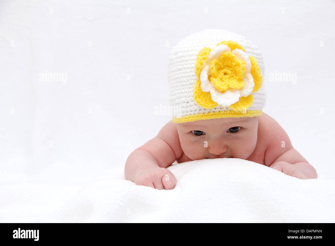 Bébé avec un chapeau blanc tricoté avec une fleur Banque D'Images