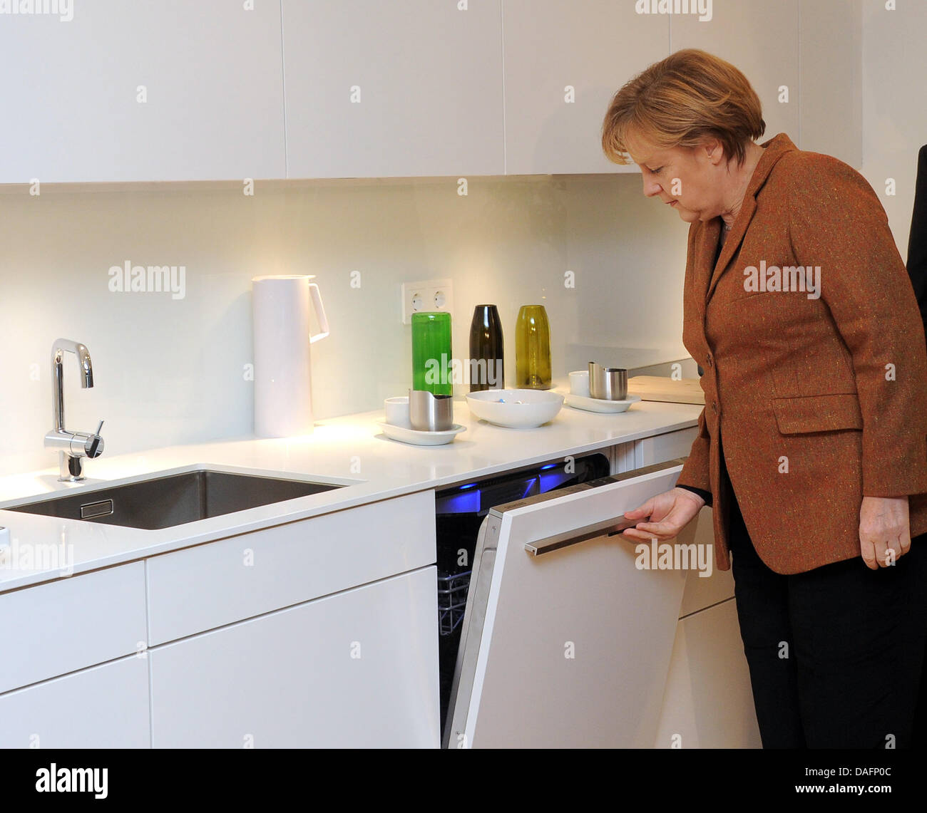 La chancelière allemande Angela Merkel cherche dans le lave-vaisselle dans la cuisine de l'efficacité énergétique à Berlin, Allemagne, 07 décembre 2011. La maison modèle est équipé de la plus moderne et la technologie de gestion de l'énergie photovoltaïque et produit deux fois autant d'énergie qu'il utilise seulement. Photo : BERND SETTNIK Banque D'Images