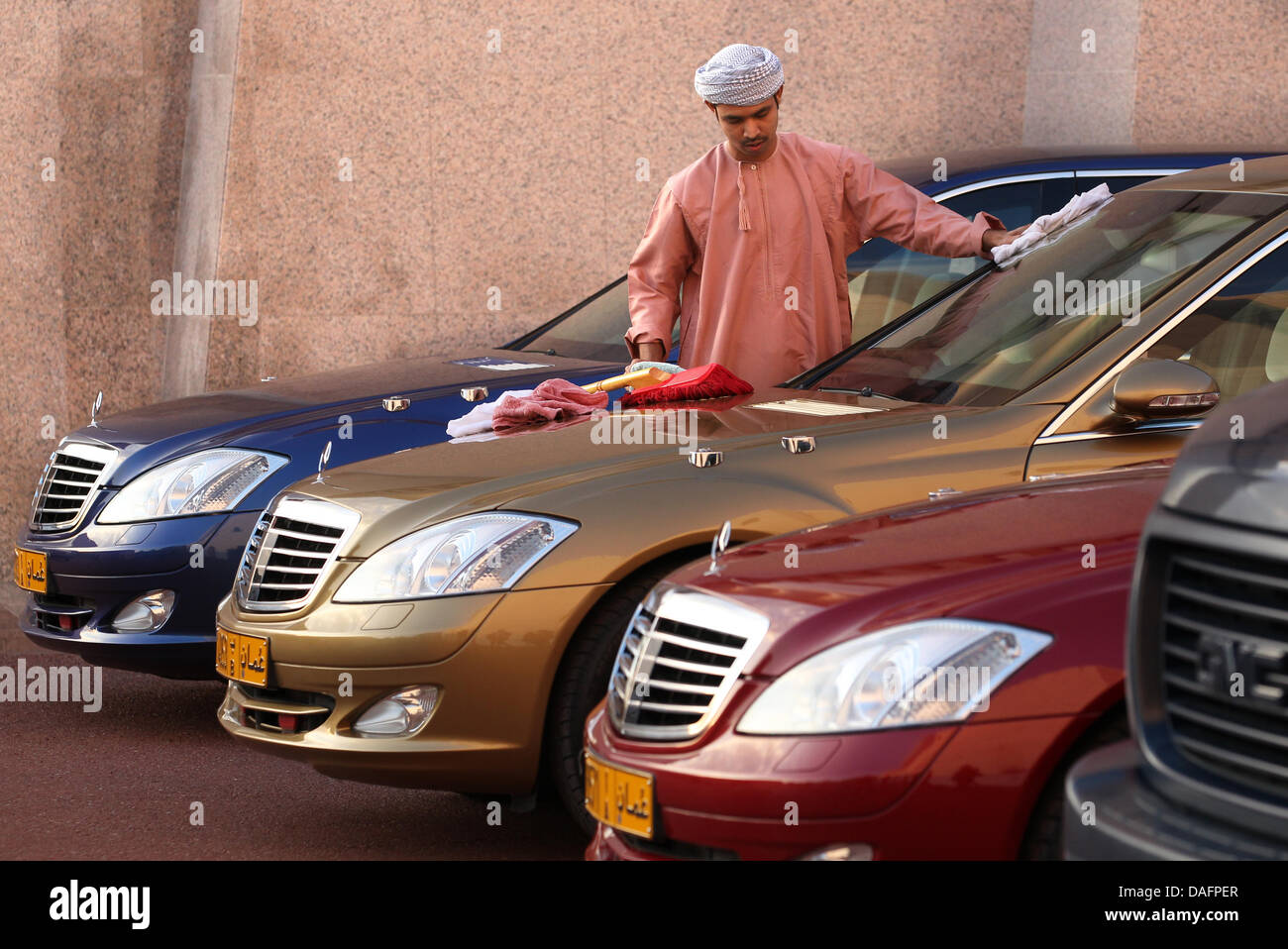 Un palais employé nettoie le sable et poussière sur des voitures à l'Al Alam Palace à Muscat, Oman, 08 décembre 2011. Le Président allemand Christian Wulff et son épouse Bettina sont sur un voyage aller-retour de six jours à travers la région de golf. Photo : WOLFGANG KUMM Banque D'Images