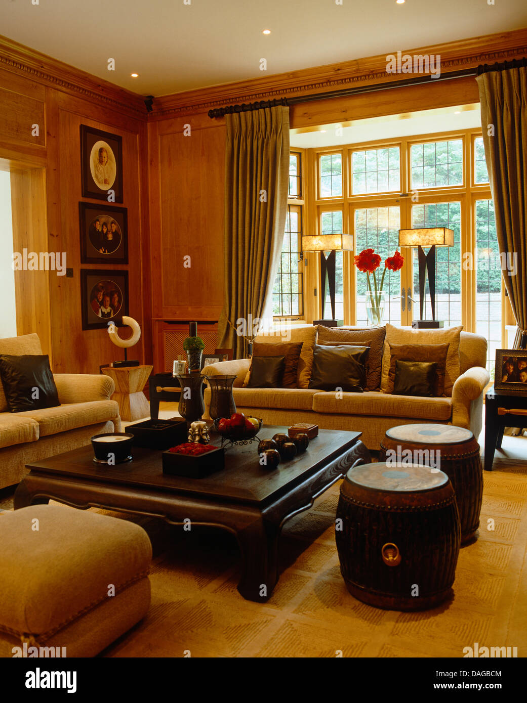 Canapé beige et le tambour autour de tabourets en bois indonésien table basse dans la salle de séjour avec lampes Art déco on windowsill Banque D'Images