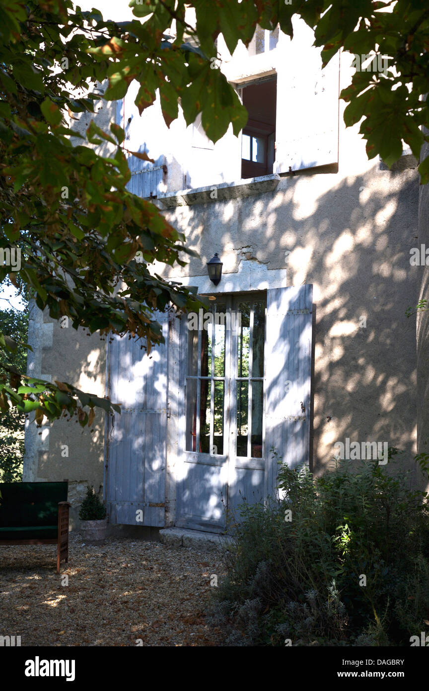 Ancienne maison de campagne française avec volets gris pâle sur double portes avec panneaux vitrés Banque D'Images