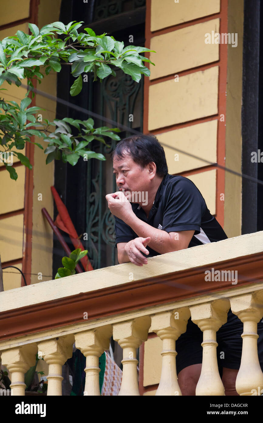 L'homme vietnamiens sur un balcon dans le vieux quartier de Hanoi, Vietnam Banque D'Images