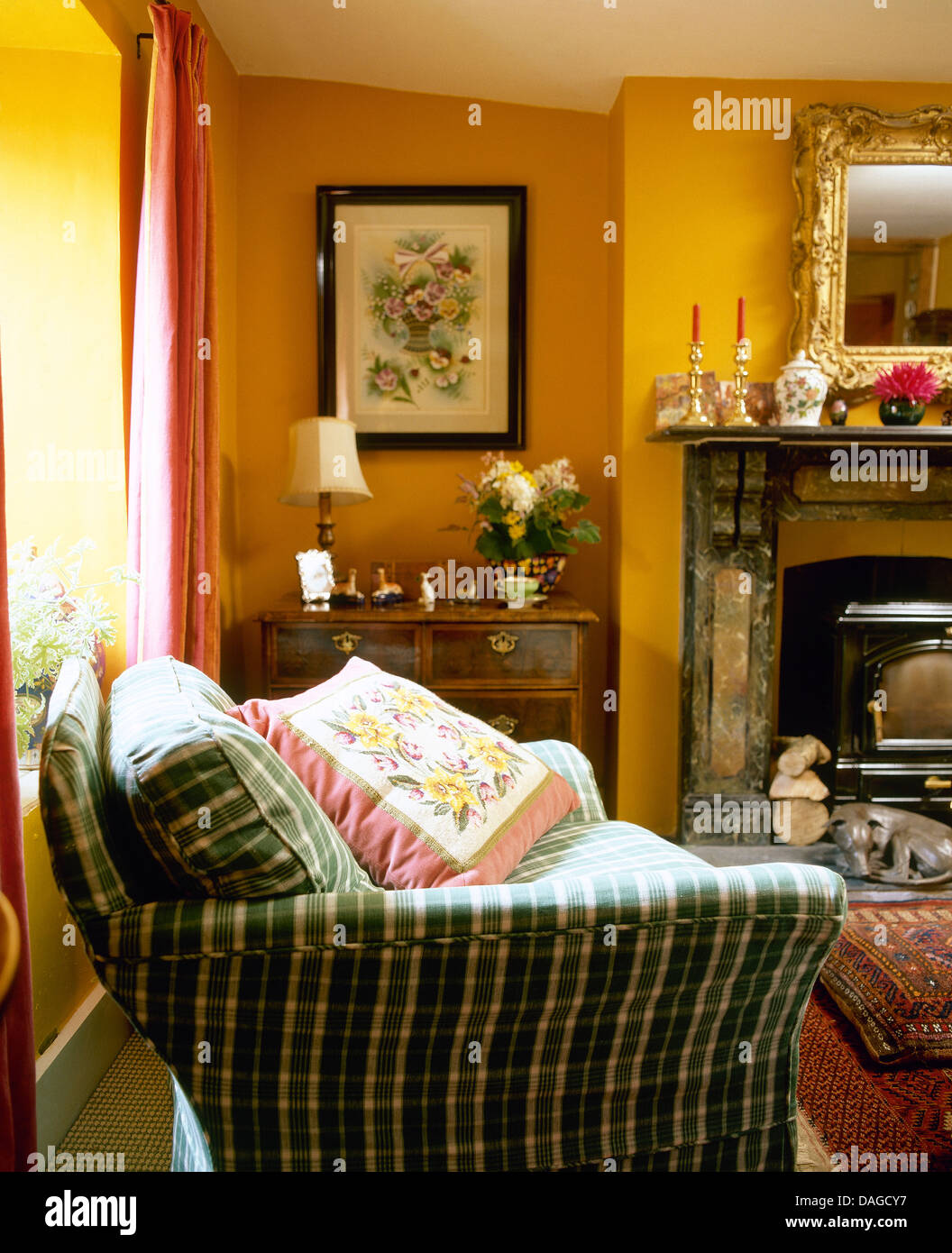 Canapé Vert vérifié avec coussin floral rose pâle en cottage orange salon avec cheminée en marbre noir Banque D'Images