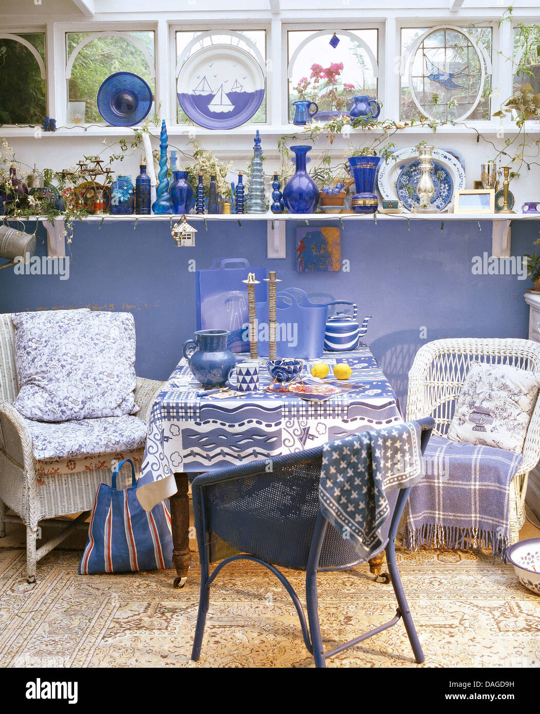 Verrerie bleu sur la tablette ci-dessous dans la fenêtre véranda cottage  salle à manger avec des chaises en osier blanc à table avec tissu bleu  Photo Stock - Alamy