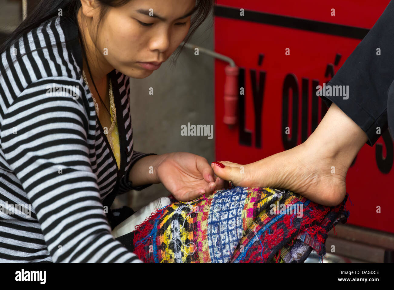 Vietnamienne faire pédicure dans les rues du vieux quartier de Hanoi, Vietnam Banque D'Images