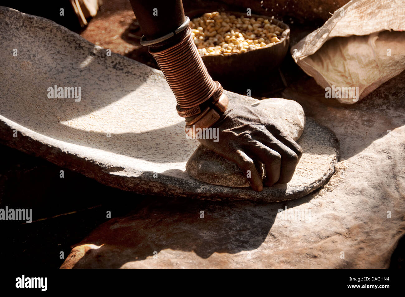 Une main d'un Suri (Surma) broyage femme farine de maïs sur une pierre, l'Ethiopie Banque D'Images