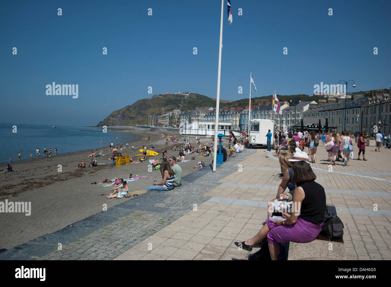 Aberystwyth, Pays de Galles, Royaume-Uni. 13 juillet 2013. Les habitants et les touristes profitent de l'été par la vague de nager dans la mer et se bronzer au soleil sur la plage à la station balnéaire d'Aberystwyth. Que les températures à travers le Royaume-Uni peuvent atteindre les 30 degrés Celsius, c'est un jour de mer plate, ciel clair, la crème glacée et crème solaire à mesure que la population d'Aberystwyth se prélasser au week-end glorieux temps. Credit : Barry Watkins/Alamy Live News Banque D'Images