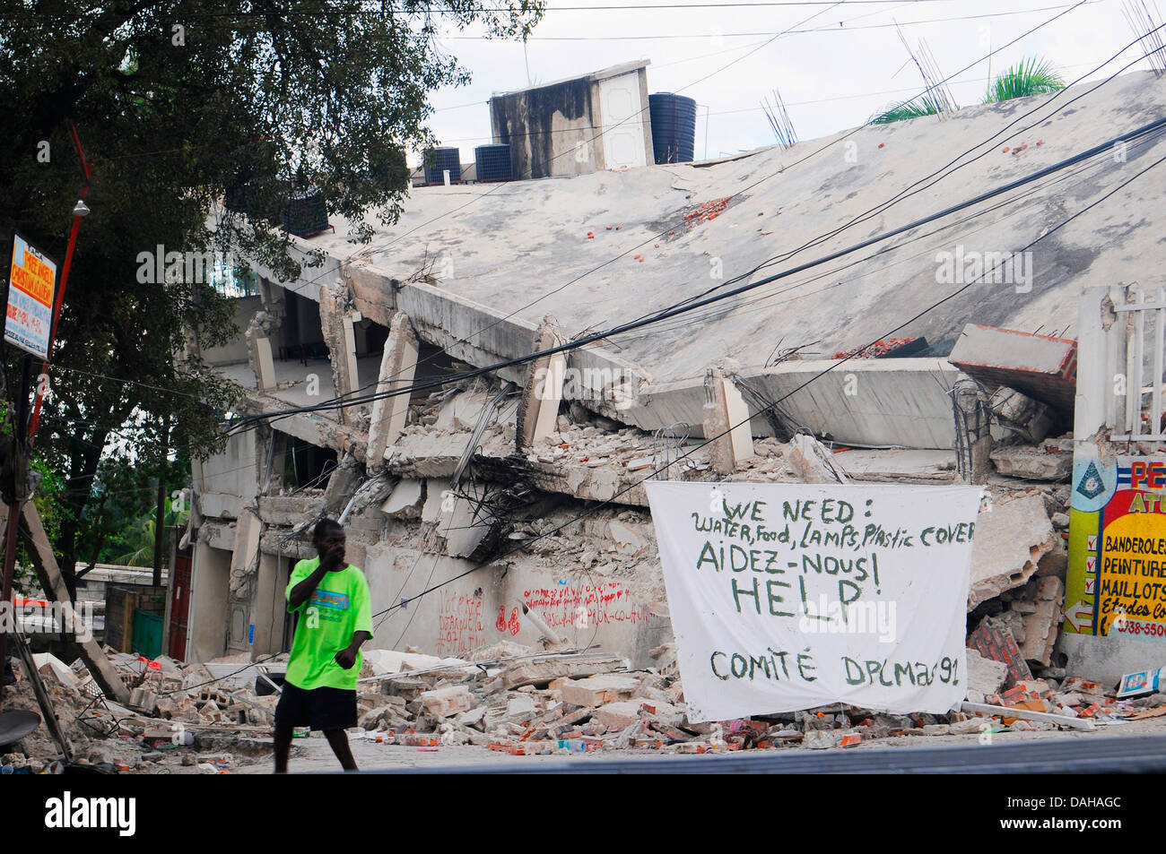 Un Haïtien passe devant un panneau qui demande de l'aide et des fournitures à la suite d'un séisme de magnitude 7,0 qui a tué 220 000 personnes, 18 janvier 2010 à Port-au-Prince, Haïti. Banque D'Images