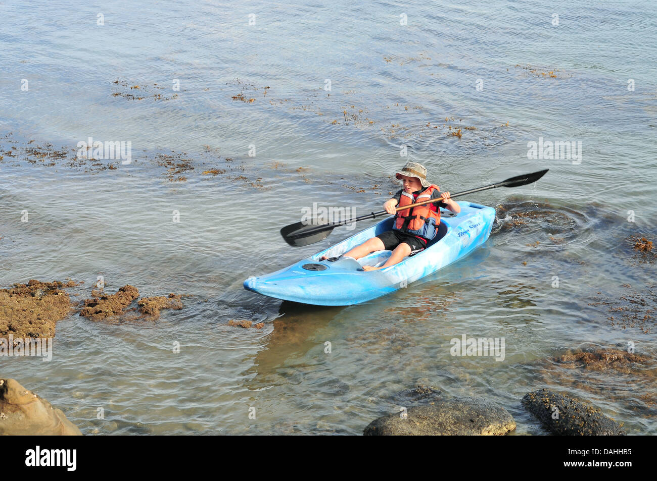 Bassin pour enfants garçon à terre en sit-on-top kayak Banque D'Images