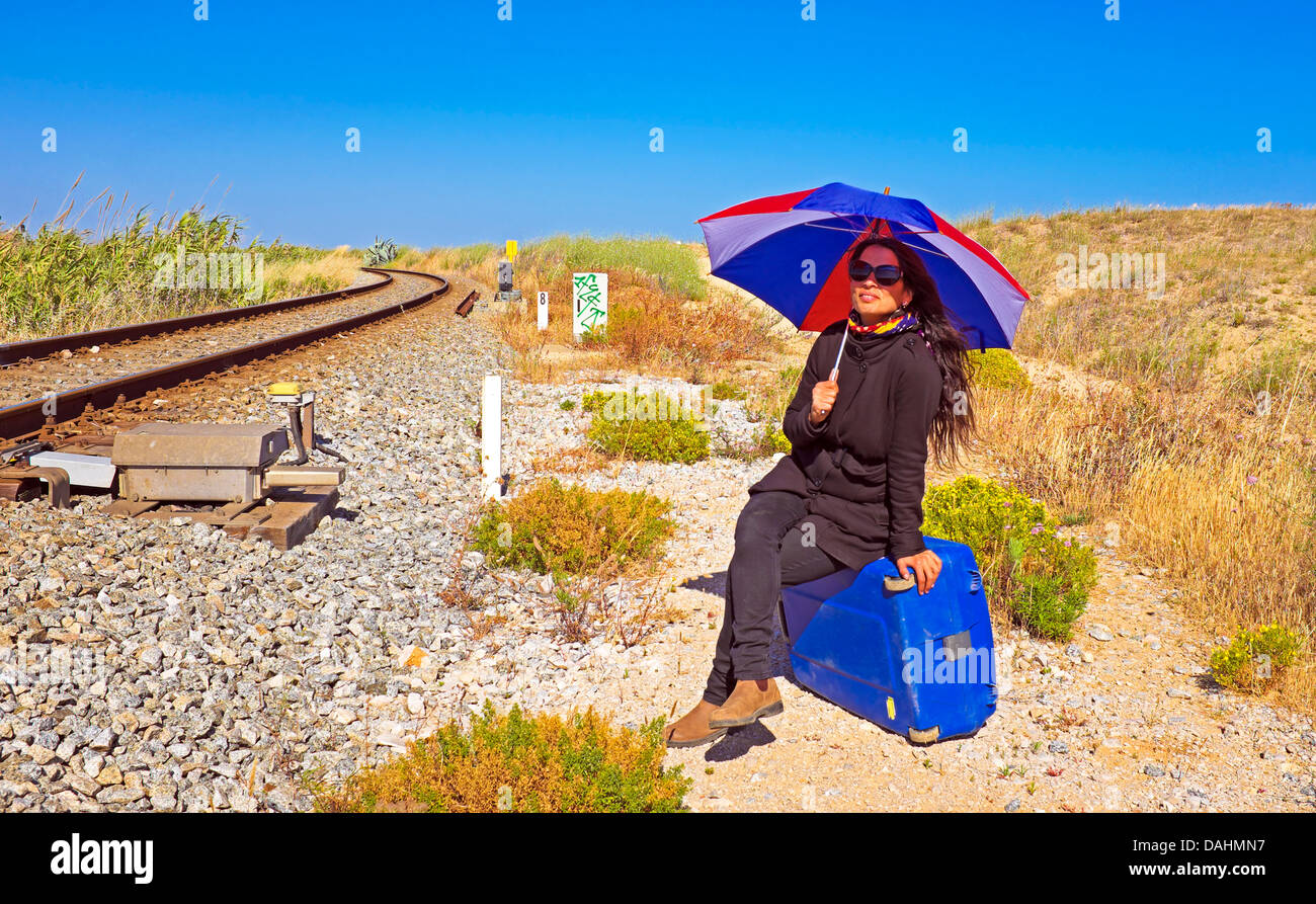 Jeune femme avec sa valise à l'attente d'une voie ferrée Banque D'Images