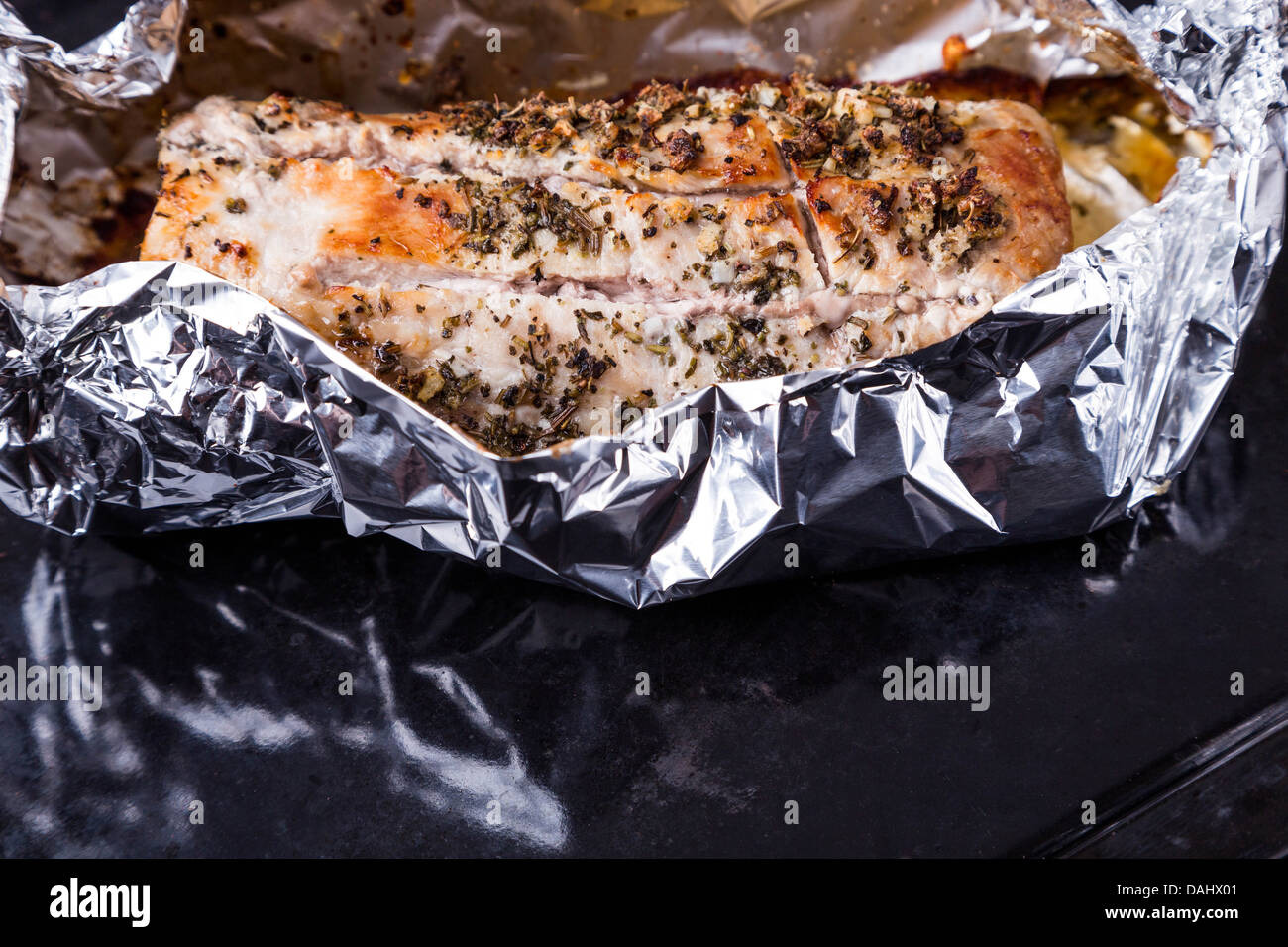 La viande de porc avec assaisonnement dans d'aluminium sur le plateau noir Banque D'Images