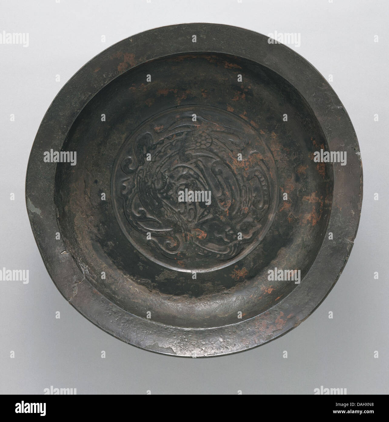 Ce bassin d'eau en bronze arbore un motif dragon et est attribué à l'artisanat chinois. Le navire, datant de la dynastie Zhou orientale, est richement moulé avec des motifs tourbillonnants et des représentations symboliques, mettant en évidence les techniques complexes de travail des métaux de l'époque. Banque D'Images