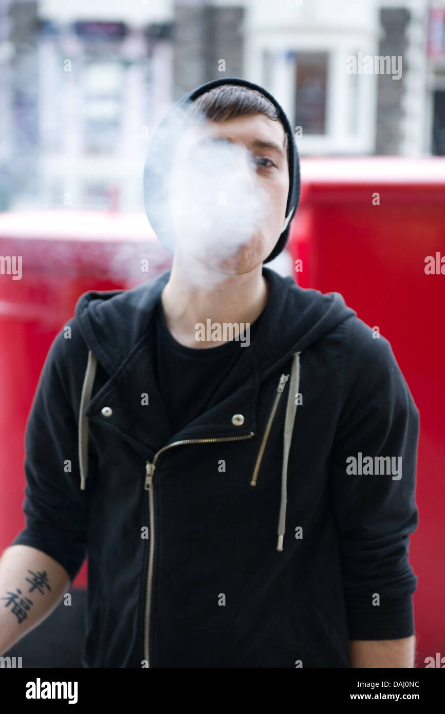 Un jeune homme soufflant la fumée de cigarette. Banque D'Images